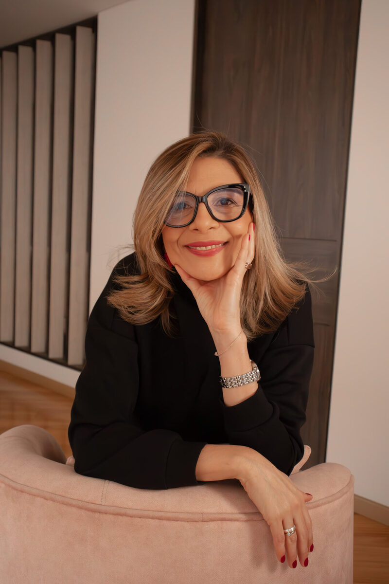 Fabiola Quintero sonríe con la mano en la mejilla, apoyada en el sillón rosa de su consulta.